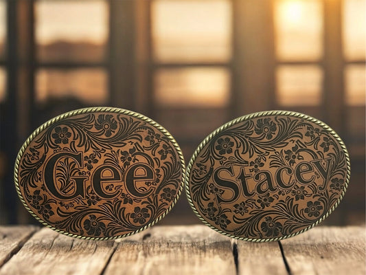 Two ornate Western belt buckles with leather inserts personalized with Gee and Stacey.