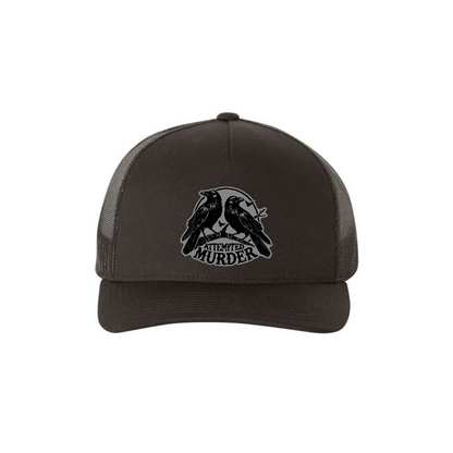 Attempted Murder 5-panel trucker hat in black, front product mockup showing a grey crow design patch.