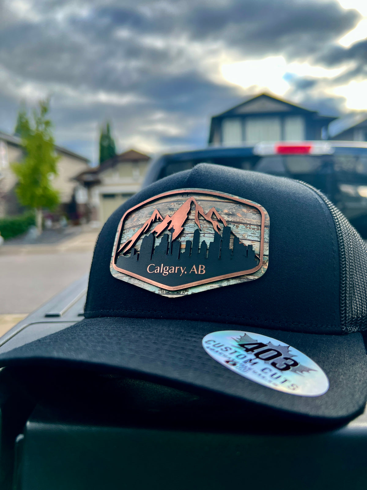 Black Calgary Skyline trucker hat with a shaped cityscape patch featuring mountains and downtown buildings, angled front view.