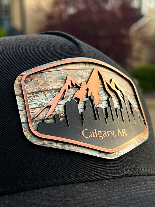 Close-up of the Calgary Skyline patch showing mountains, city buildings, and Calgary AB lettering on a black hat.