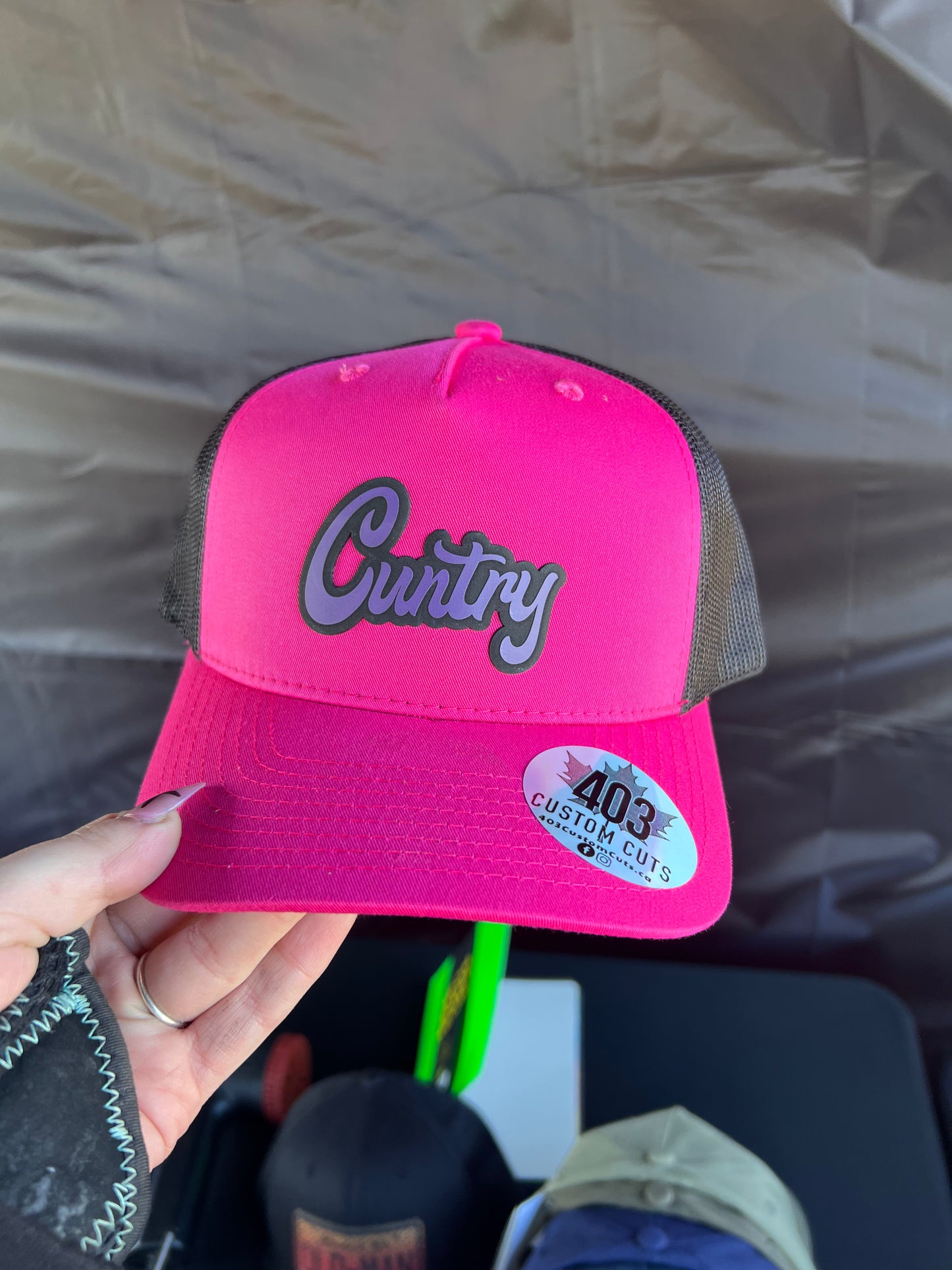 Hot pink Cuntry snapback trucker hat with a purple script patch, front view.