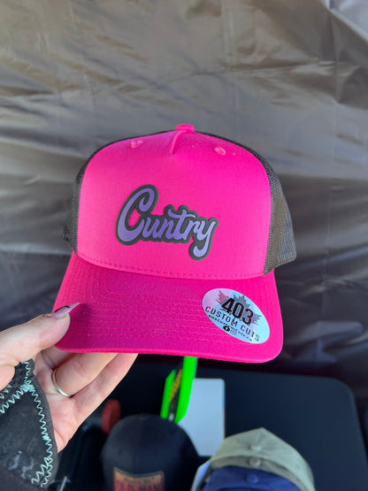 Hot pink Cuntry snapback trucker hat with a purple script patch, front view.