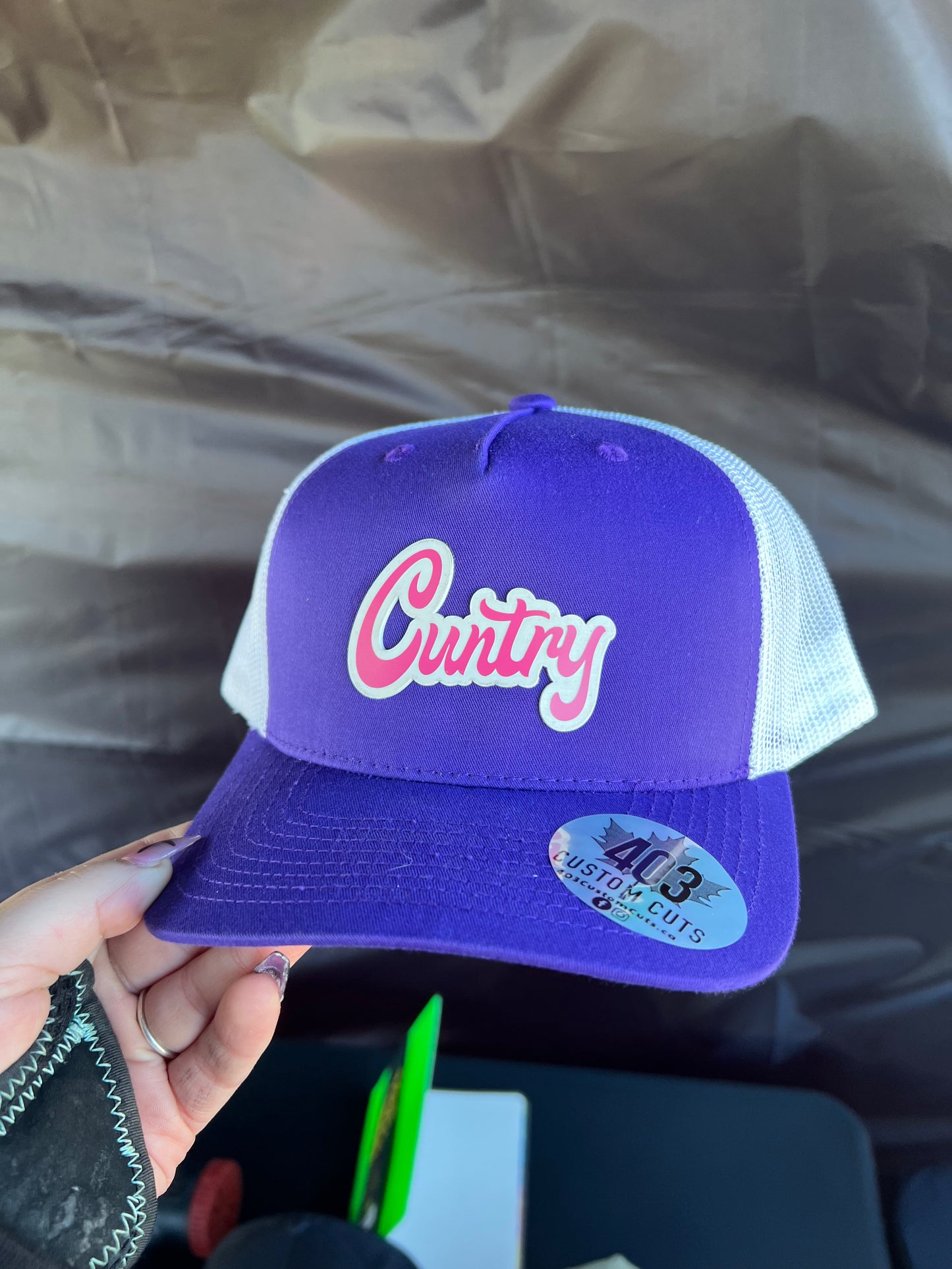Purple and white Cuntry snapback trucker hat with a pink and white script patch, front view.