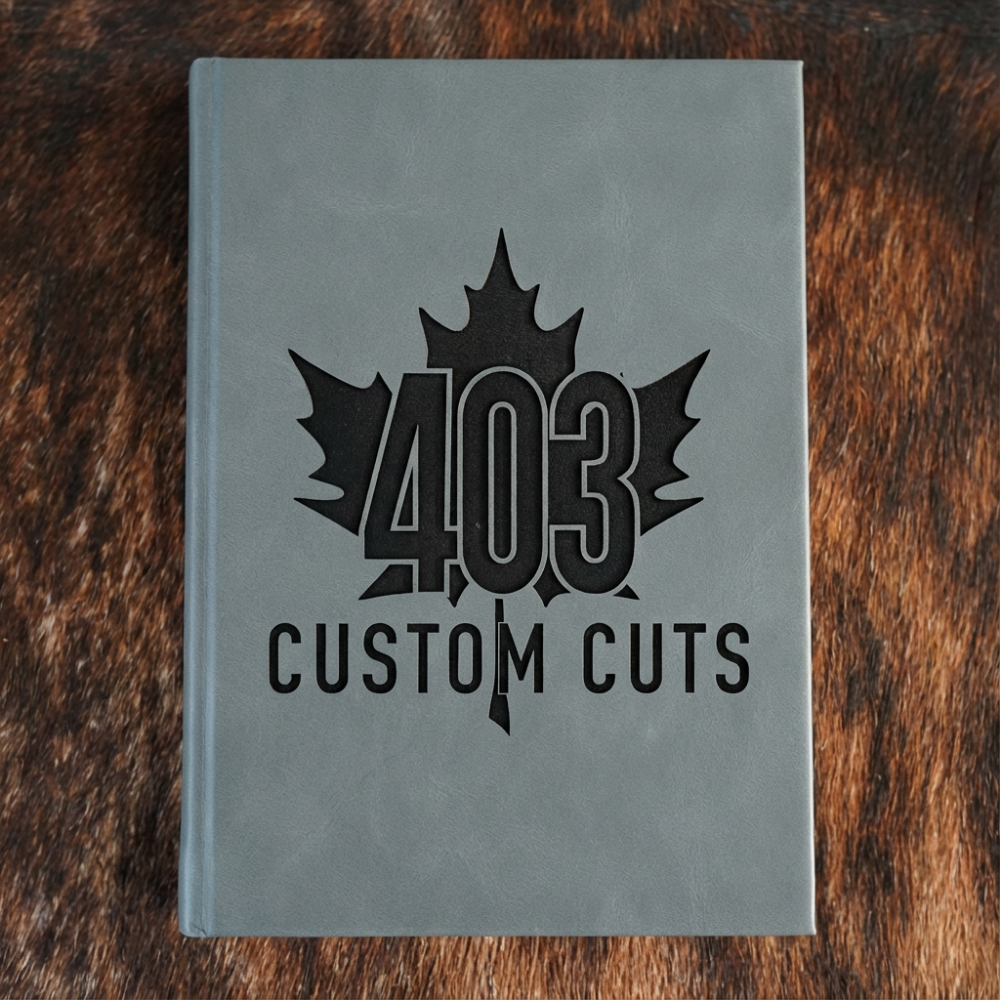Charcoal leatherette journal with the engraved 403 Custom Cuts maple leaf logo on the cover.