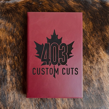 Maroon leatherette journal with the engraved 403 Custom Cuts maple leaf logo on the cover.