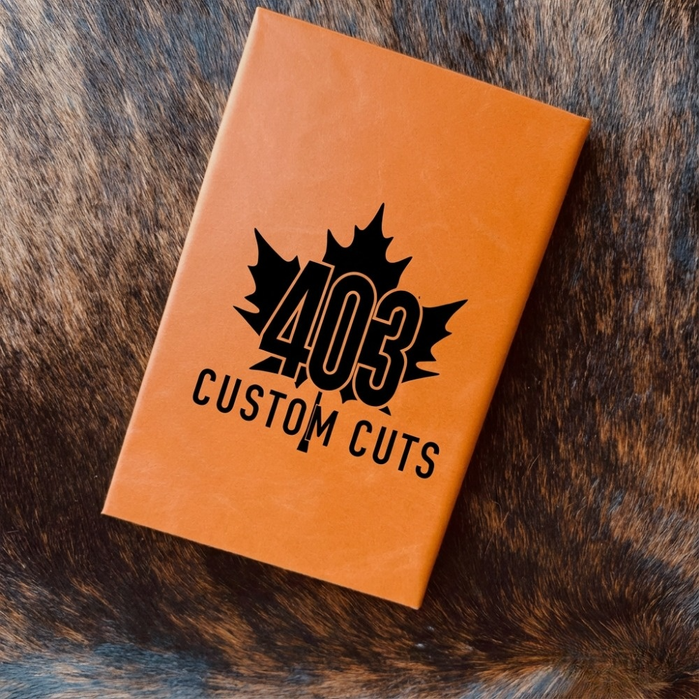 Orange leatherette journal with the engraved 403 Custom Cuts maple leaf logo on the cover.