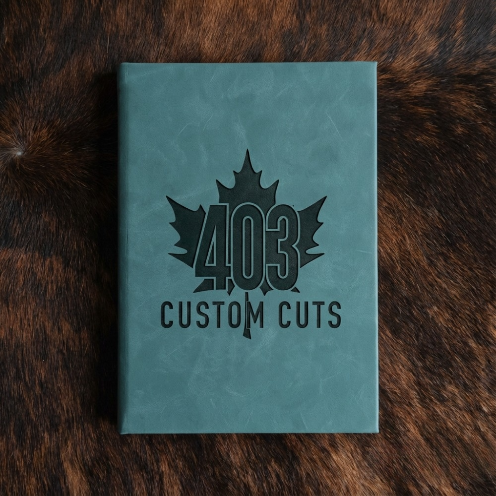 Topaz leatherette journal with the engraved 403 Custom Cuts maple leaf logo on the cover.