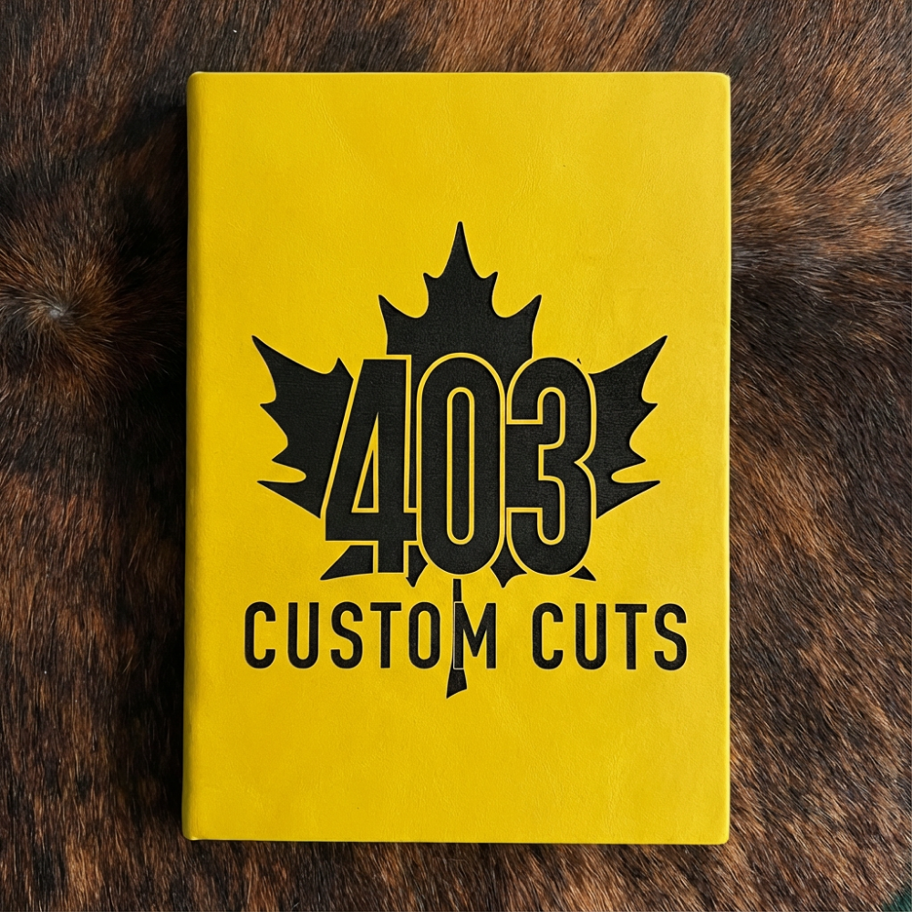 Yellow leatherette journal with the engraved 403 Custom Cuts maple leaf logo on the cover.