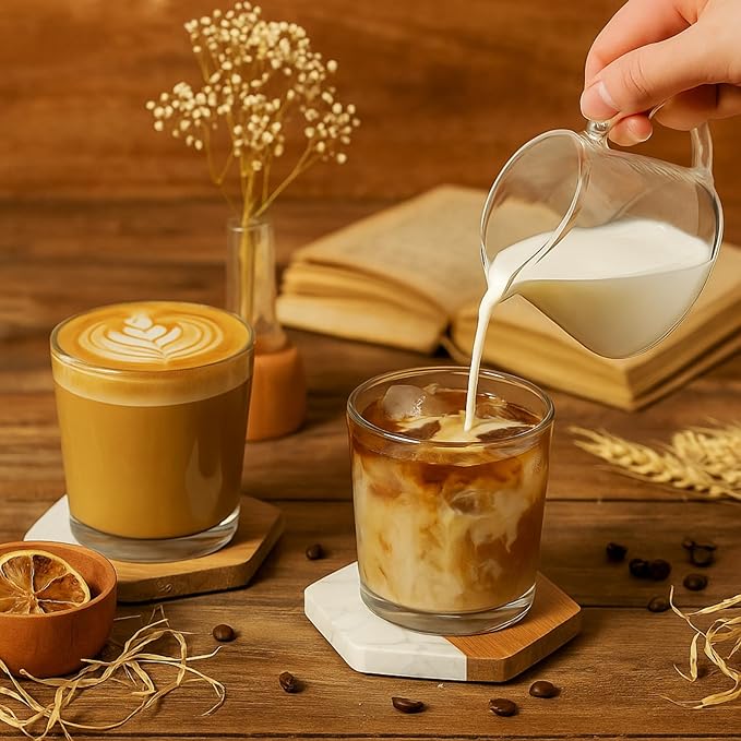 Coffee glasses resting on hexagonal marble and wood coasters on a table.