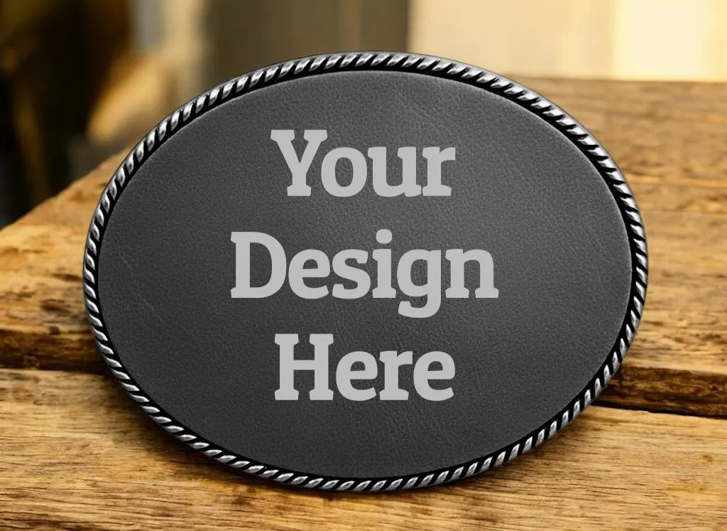 Oval silver belt buckle with a black leather insert and Your Design Here sample text.
