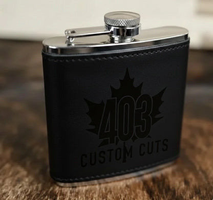 Black leatherette six-ounce flask with a black engraved 403 Custom Cuts logo.