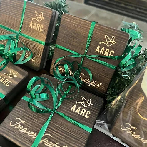 Engraved wooden coaster gift packs tied with green ribbons.