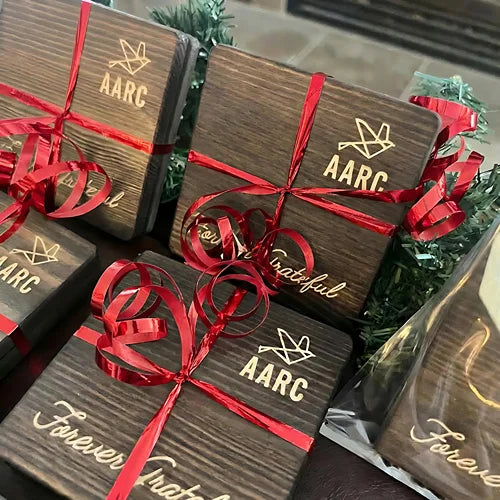 Engraved wooden coaster gift packs tied with red ribbons.