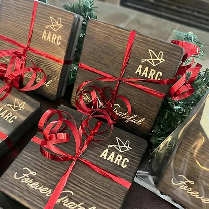 Engraved wooden coaster gift packs tied with red ribbons.