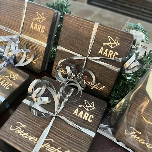 Engraved wooden coaster gift packs tied with silver ribbons.