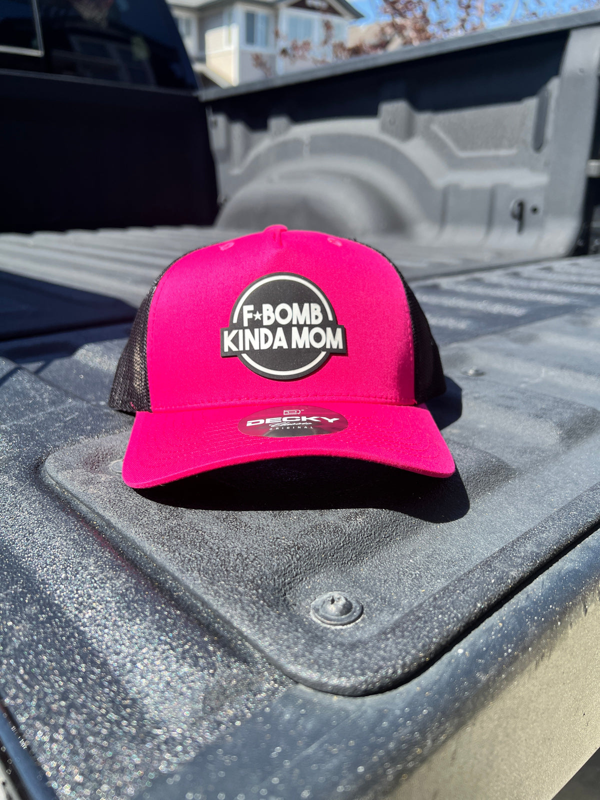 Hot pink and black F*Bomb Kinda Mom trucker hat with a round black and white patch, front view.
