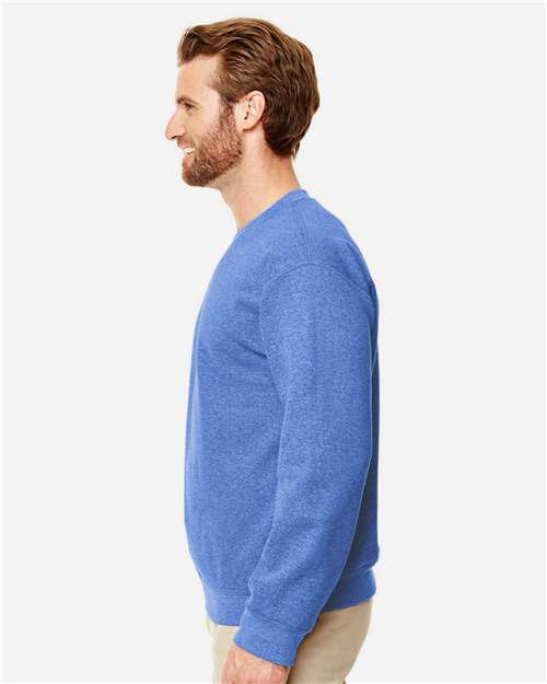 Model wearing a Gildan 18000 Heavy Blend crewneck sweatshirt in Heather Deep Royal, side view.
