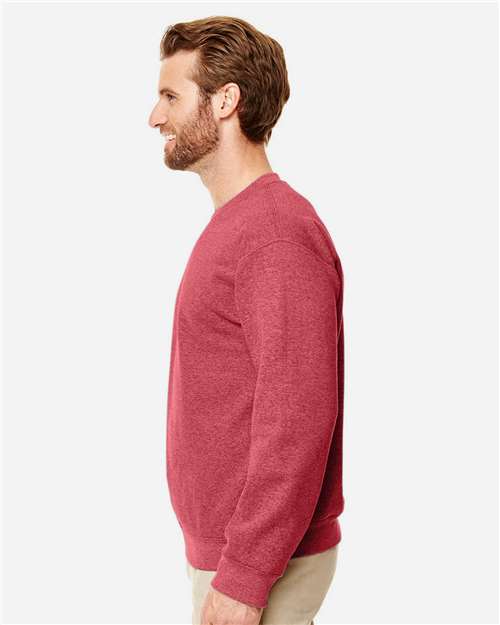 Model wearing a Gildan 18000 Heavy Blend crewneck sweatshirt in Heather Scarlet Red, side view.