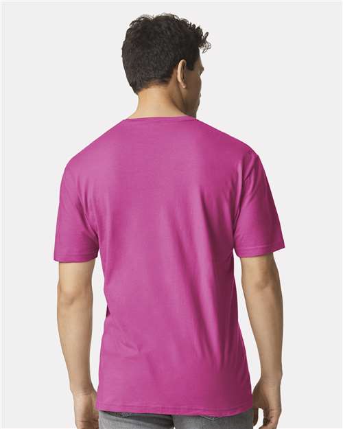 Model wearing a Gildan 64000 Softstyle T-shirt in Heliconia, back view.