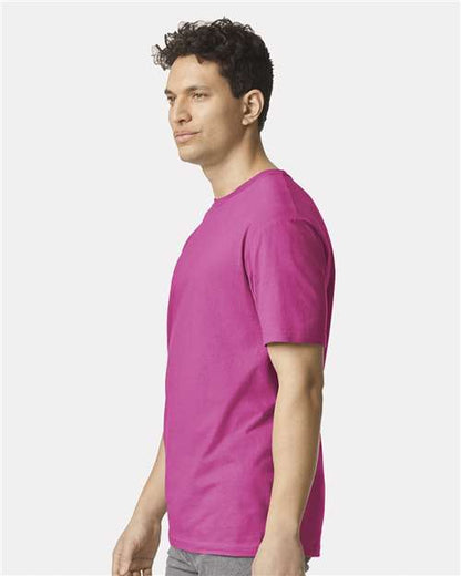 Model wearing a Gildan 64000 Softstyle T-shirt in Heliconia, side view.