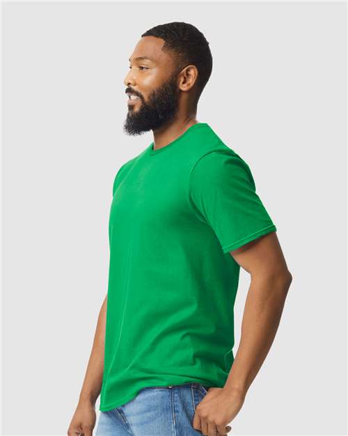 Model wearing a Gildan 64000 Softstyle T-shirt in Irish Green, side view.