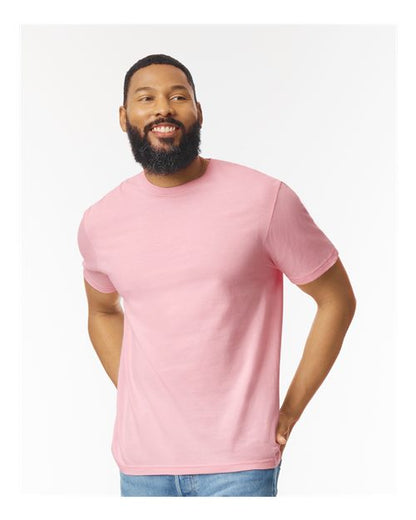 Model wearing a Gildan 64000 Softstyle T-shirt in Light Pink, front view.