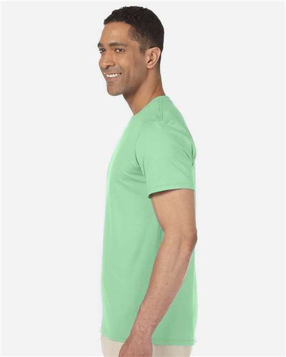 Model wearing a Gildan 64000 Softstyle T-shirt in Mint Green, side view.