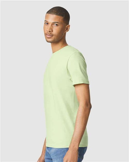 Model wearing a Gildan 64000 Softstyle T-shirt in Pistachio, side view.