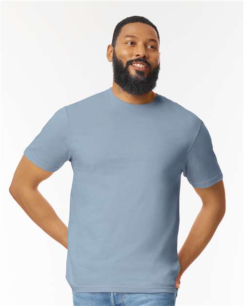 Model wearing a Gildan 64000 Softstyle T-shirt in Stone Blue, front view.