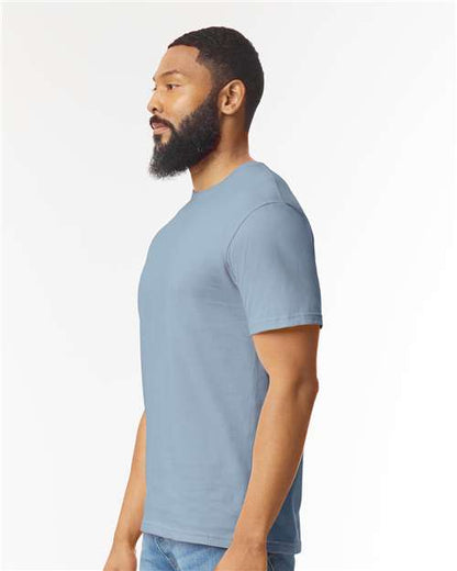 Model wearing a Gildan 64000 Softstyle T-shirt in Stone Blue, side view.
